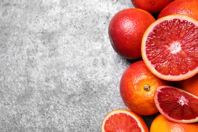 Whole and cut red oranges on grey table, flat lay. Space for text