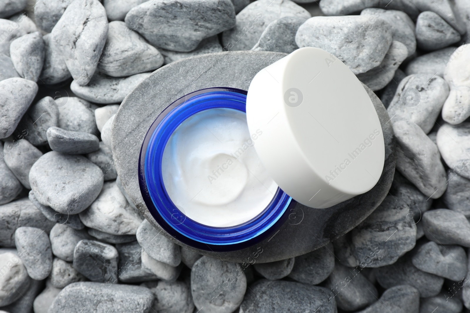 Photo of Jar of moisturizing cream on stones, top view