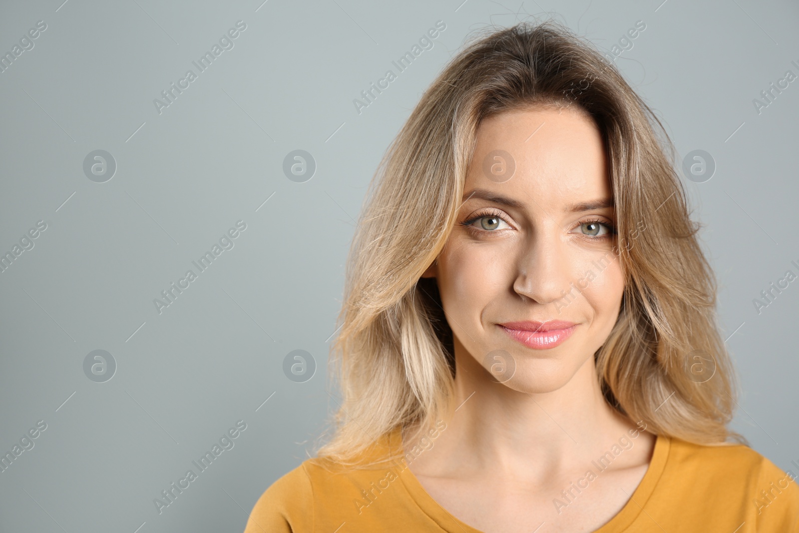 Photo of Portrait of happy young woman with beautiful blonde hair on grey background. Space for text