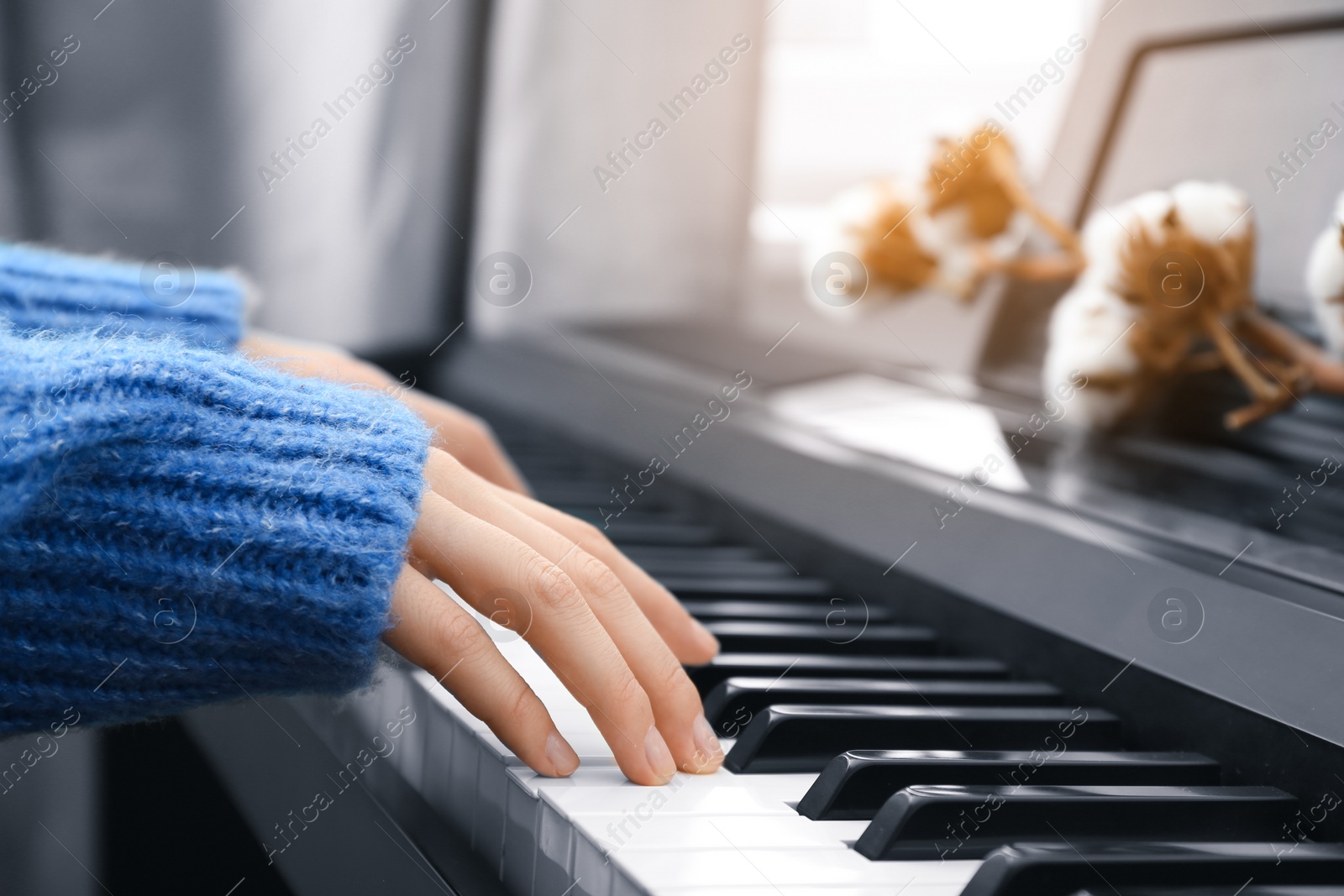 Photo of Young woman playing piano at home, closeup