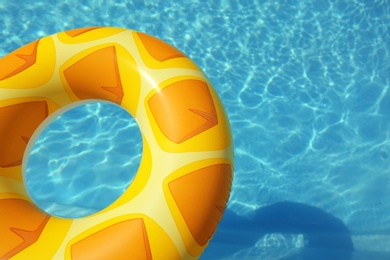 Bright inflatable ring floating in swimming pool on sunny day, above view. Space for text