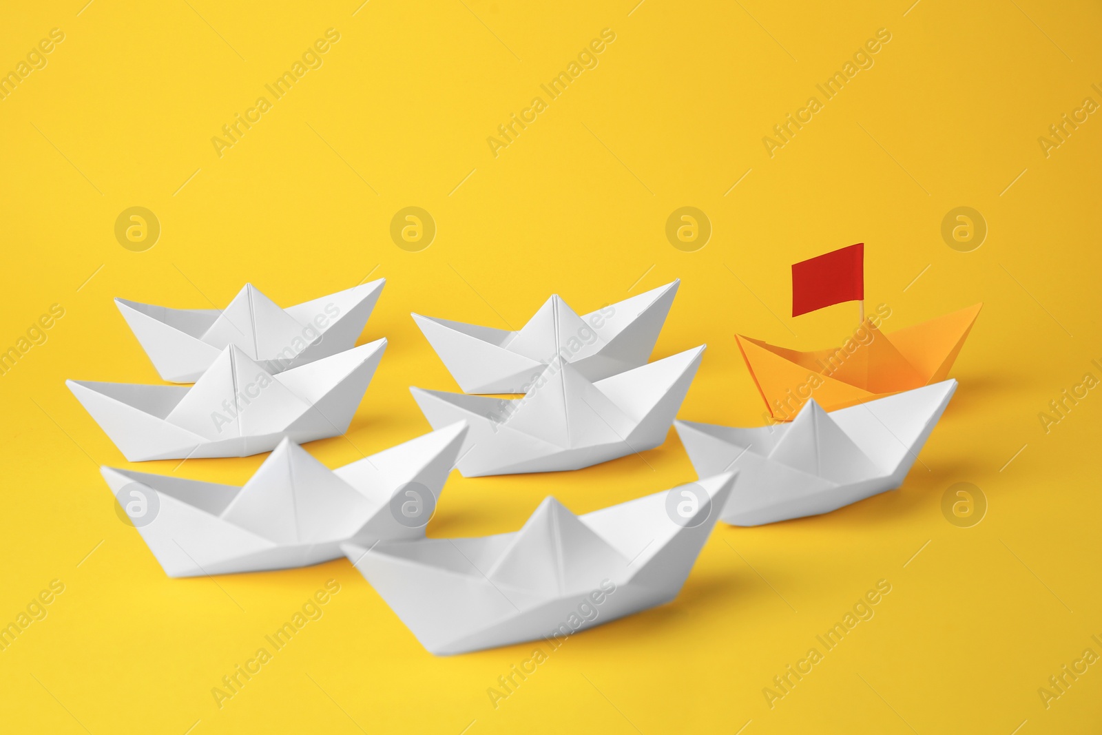 Photo of Group of paper boats following yellow one on color background. Leadership concept