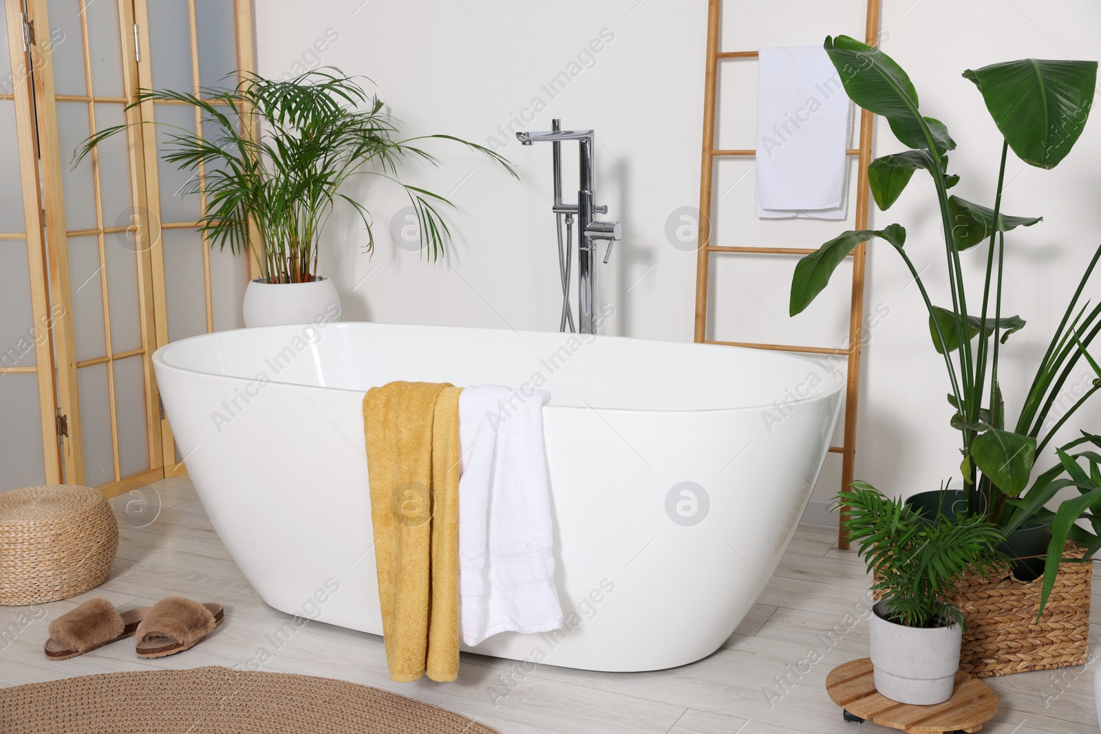 Photo of Stylish bathroom interior with modern ceramic tub and beautiful houseplants