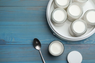 Modern yogurt maker with full jars on blue wooden table, flat lay