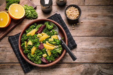 Tasty fresh kale salad on wooden table, flat lay. Food photography  