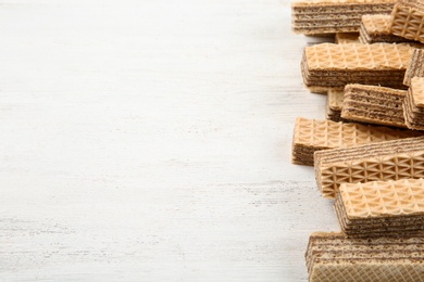 Delicious crispy wafers with chocolate filling on white wooden table. Space for text