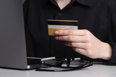 Photo of Online payment. Woman with laptop and credit card at white wooden table, closeup