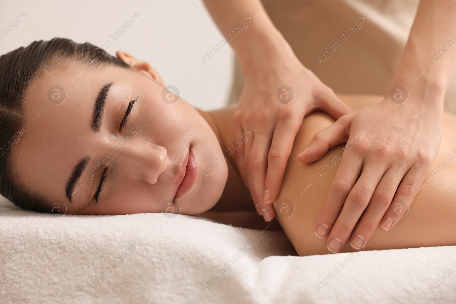 Photo of Woman receiving back massage on couch in spa salon