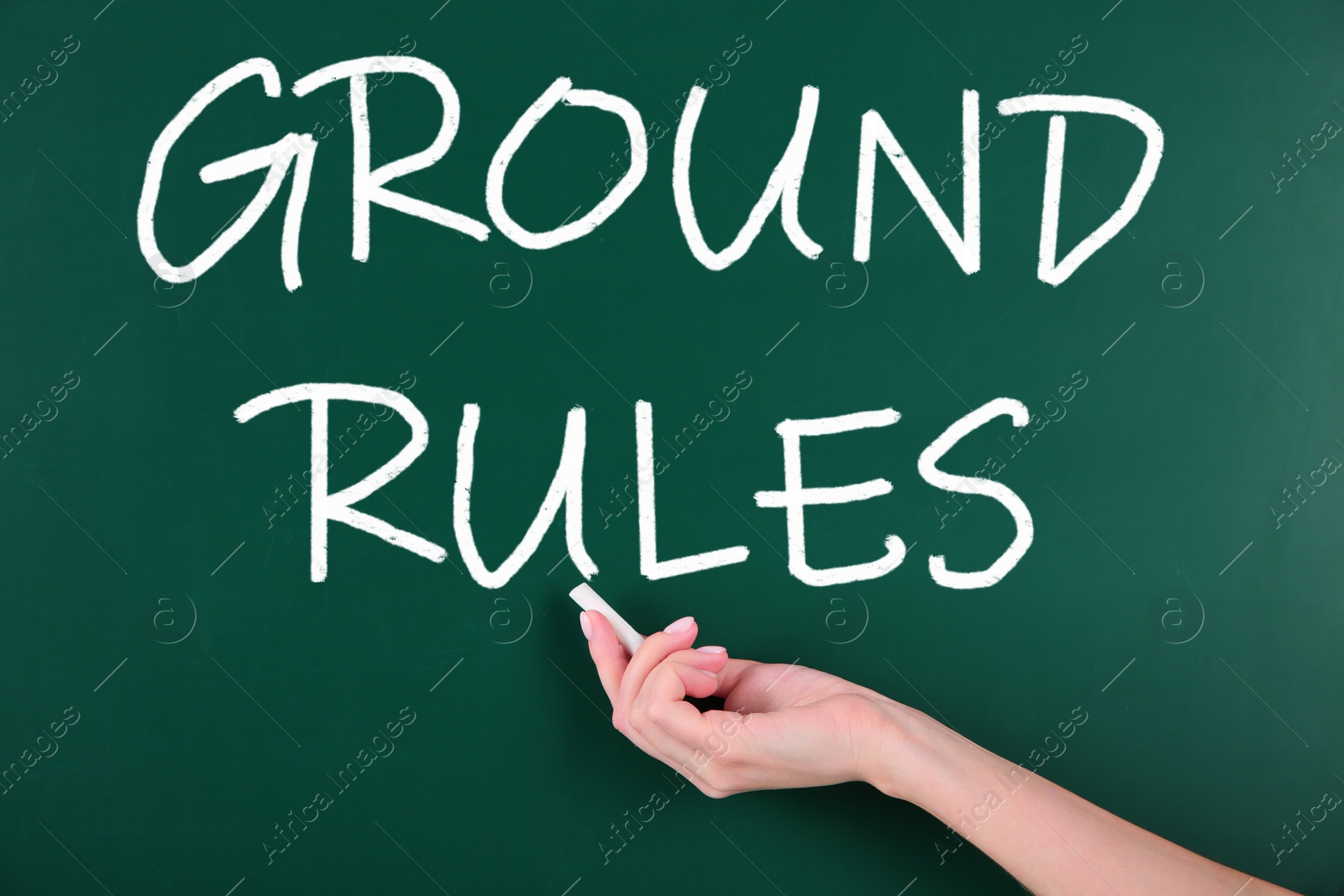 Image of Woman writing phrase GROUND RULES on chalkboard, closeup