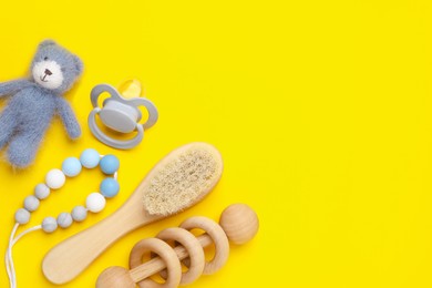 Flat lay composition with pacifier and other baby stuff on yellow background. Space for text