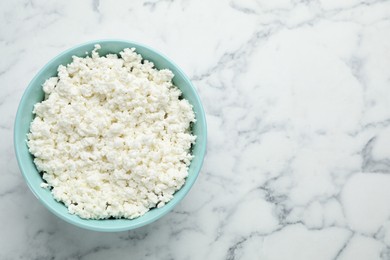 Photo of Delicious fresh cottage cheese in bowl on white marble table, top view. Space for text