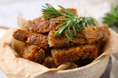Delicious crispy rusks with rosemary in bowl, closeup view
