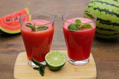 Photo of Glasses of delicious watermelon smoothie with mint and lime on wooden table