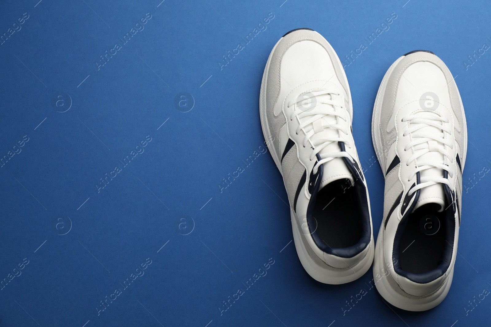 Photo of Pair of stylish sports shoes on blue background, flat lay. Space for text