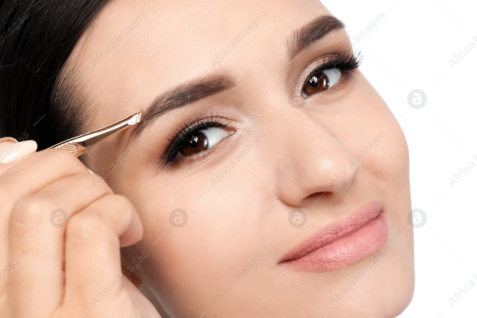 Photo of Young woman plucking eyebrow with tweezers, closeup