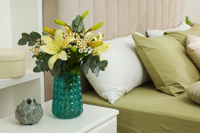 Photo of Bouquet of beautiful flowers and ceramic decor on nightstand in bedroom