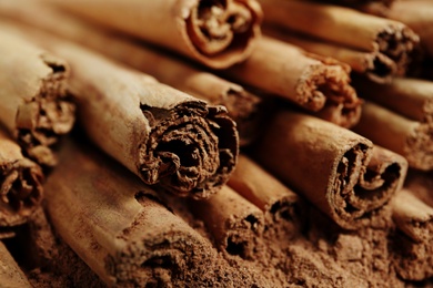 Photo of Cinnamon sticks and powder as background, closeup