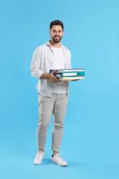 Happy man with folders on light blue background