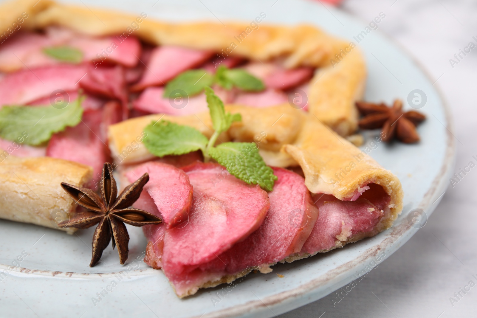 Photo of Delicious apple galette with mint and star anise on white marble table, closeup