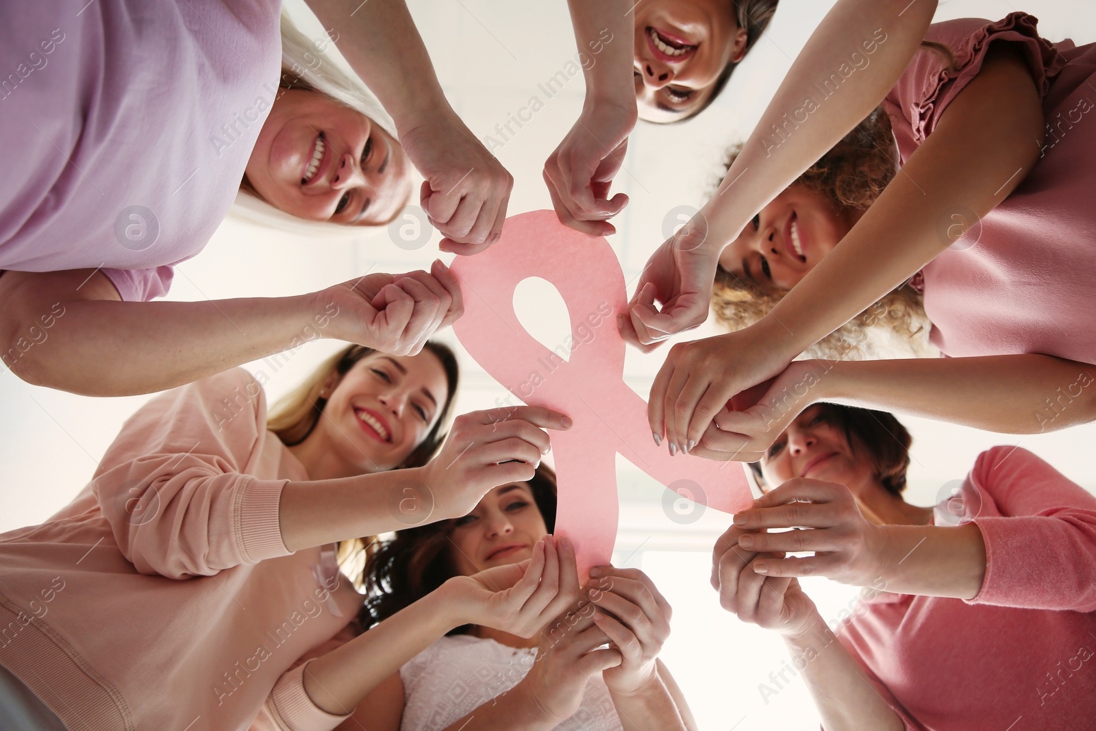 Photo of Women holding pink paper ribbon, bottom view. Breast cancer awareness concept