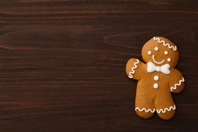 Photo of Gingerbread man on wooden table, top view with space for text. Delicious Christmas cookie