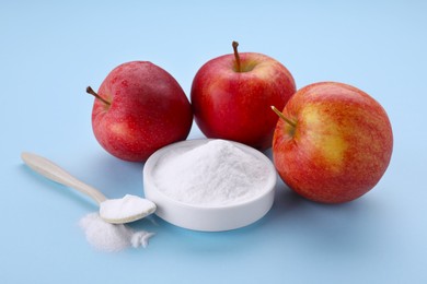 Photo of Sweet powdered fructose and fresh apples on light blue background