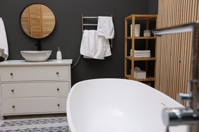 Photo of Stylish bathroom interior with heated towel rail and white tub