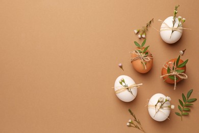 Photo of Happy Easter. Festive composition with eggs and floral decor on brown background, flat lay. Space for text.