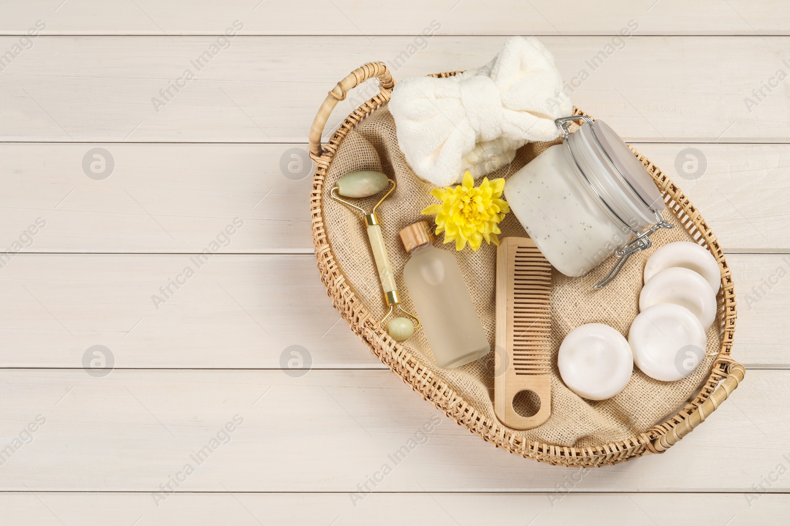 Photo of Spa gift set with different products in wicker basket on white wooden table, top view. Space for text