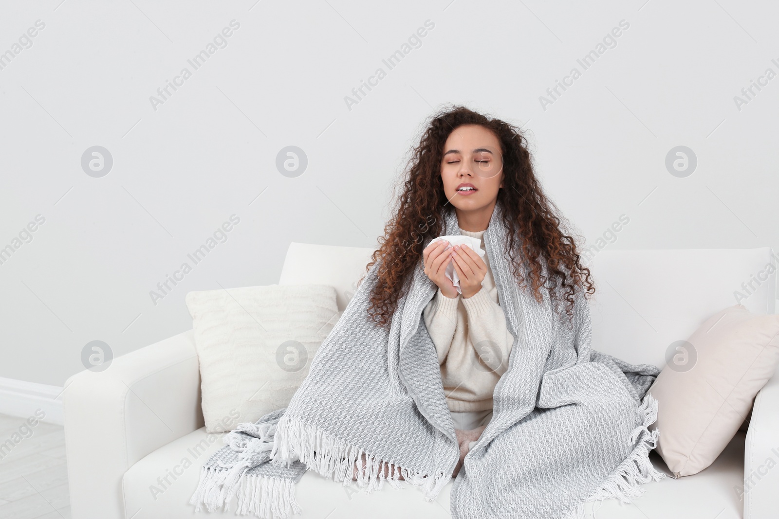 Photo of Sick African American woman sneezing at home, space for text