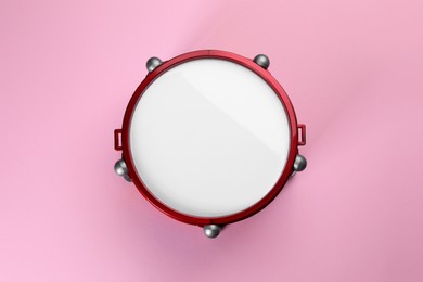 Photo of One children's drum on pink background, top view. Percussion musical instrument