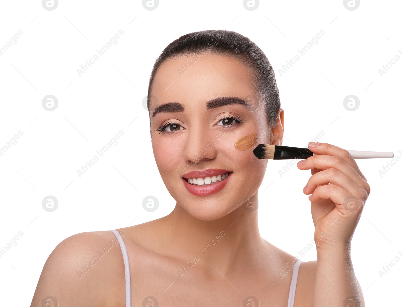 Photo of Woman applying foundation on face with brush against white background