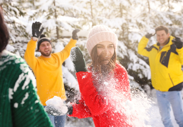 Happy friends playing snowballs outdoors. Winter vacation