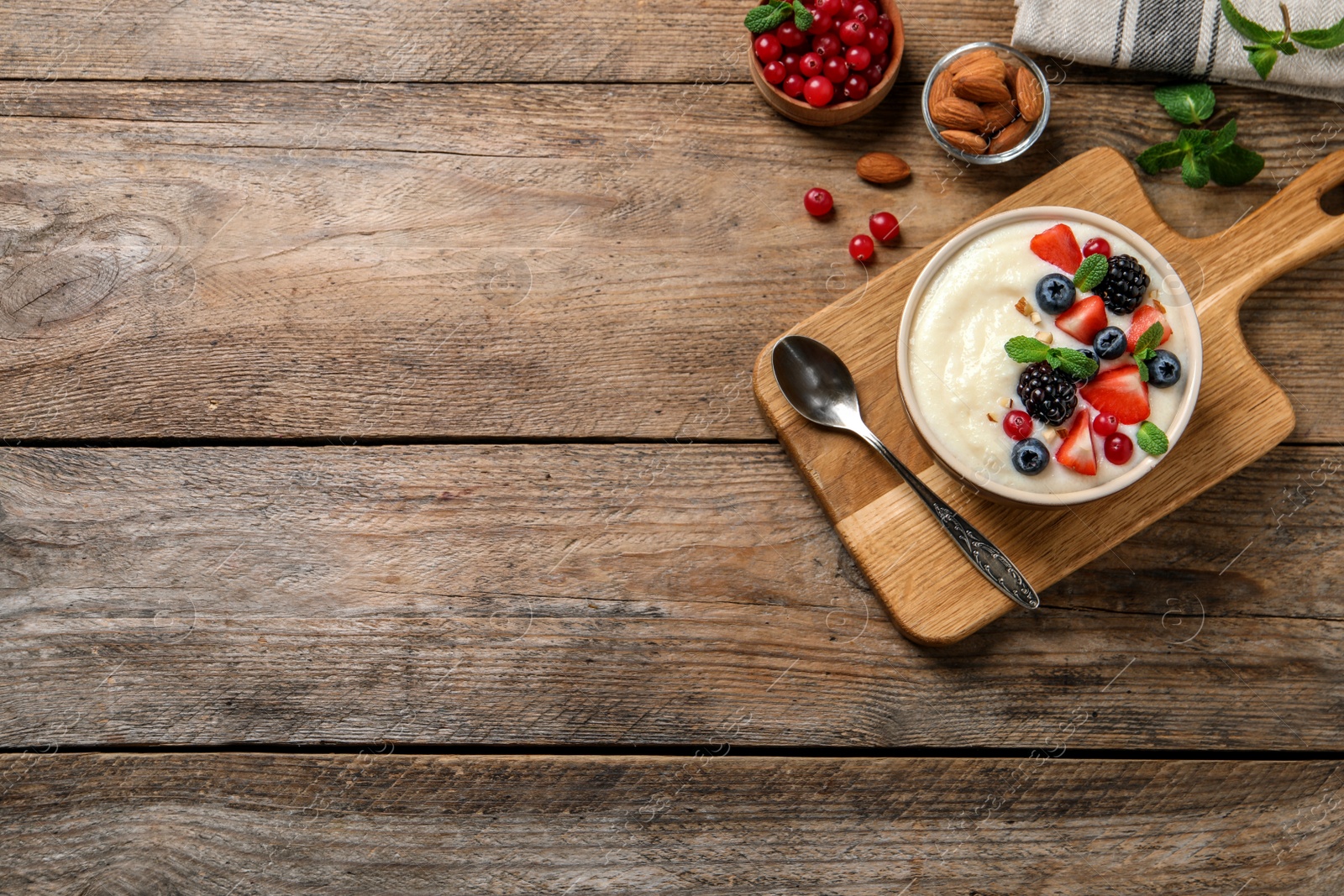 Photo of Delicious semolina pudding with berries on wooden table, flat lay. Space for text