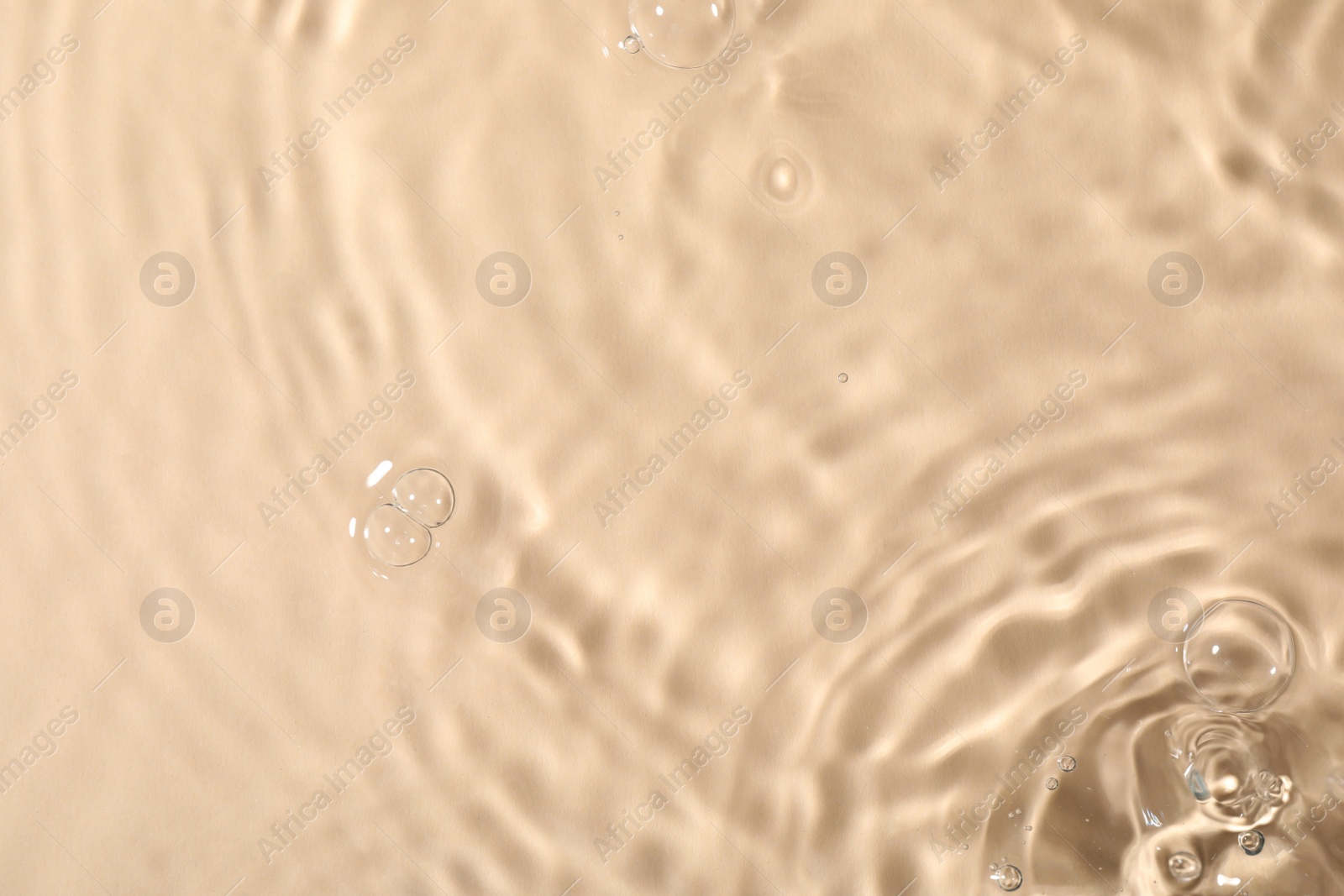 Photo of Closeup view of water with rippled surface on beige background