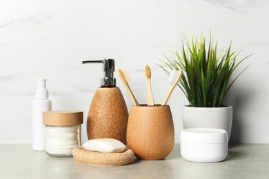 Different bath accessories and personal care products on gray table near white marble wall