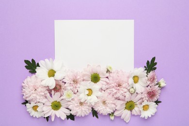 Photo of Beautiful chrysanthemum flowers and blank card on violet background, flat lay. Space for text
