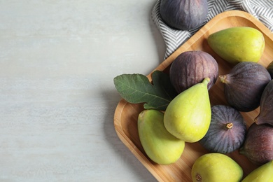 Photo of Plate with assorted ripe figs on light background, top view. Space for text