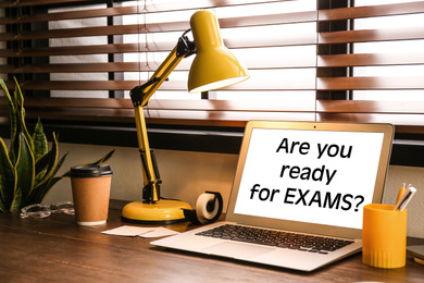 Image of Modern laptop with phrase ARE YOU READY FOR EXAMS on table in office