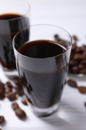 Photo of Shot glasses of coffee liqueur on white table, closeup