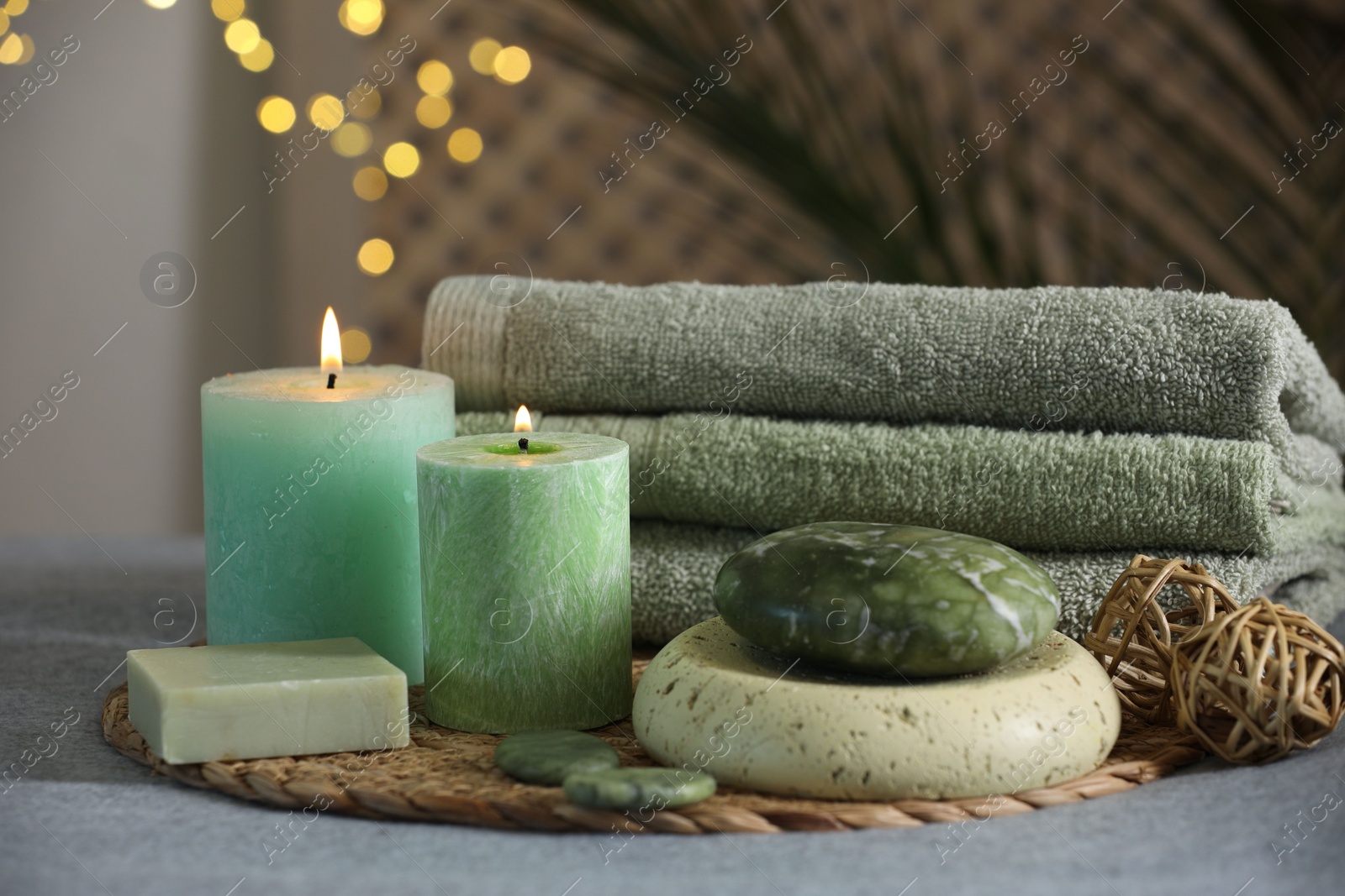 Photo of Spa composition. Burning candles, stones, soap and towels on grey table