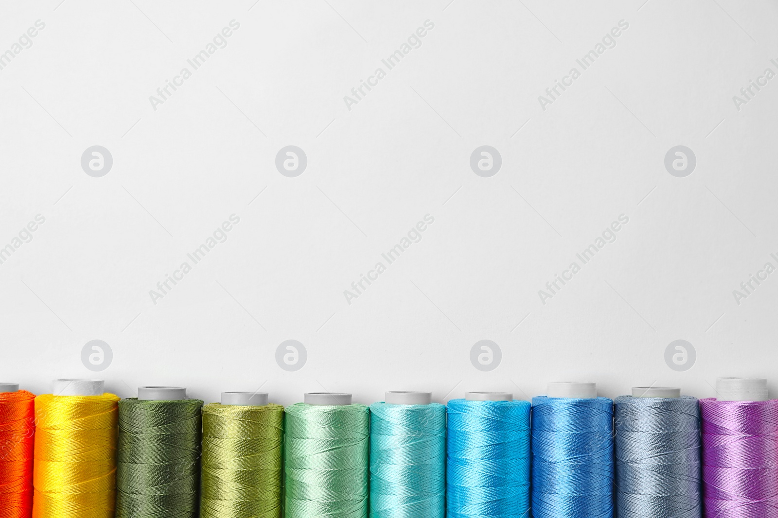 Photo of Color sewing threads on white background, top view