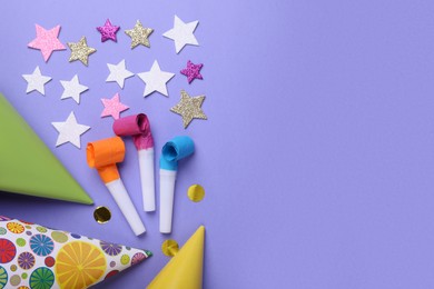 Party hats, blowers and confetti for birthday party on violet background, flat lay. Space for text