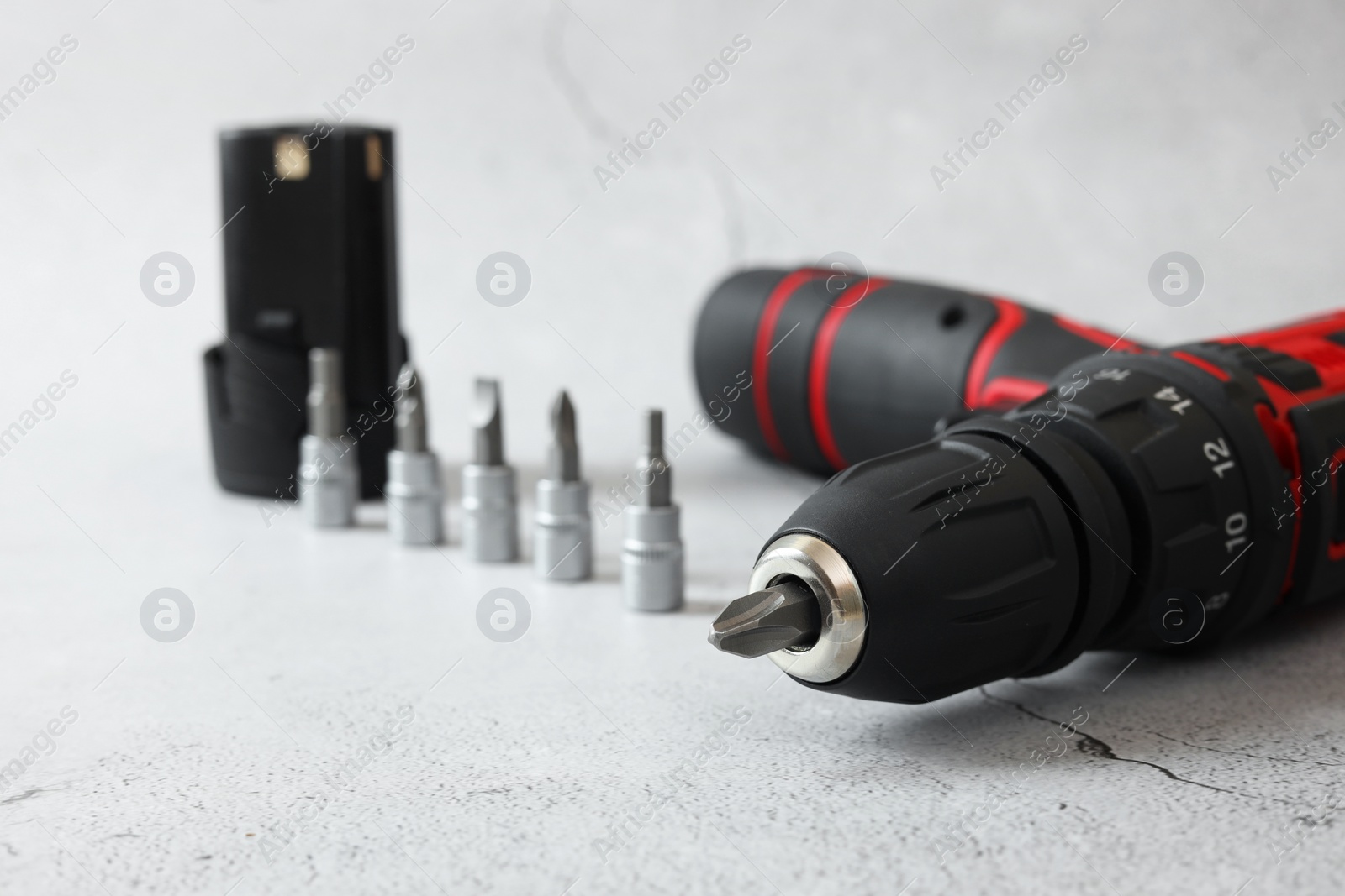 Photo of Electric screwdriver, drill bits and battery on light table, closeup
