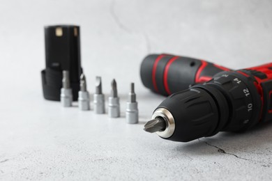 Photo of Electric screwdriver, drill bits and battery on light table, closeup