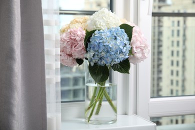 Photo of Beautiful hydrangea flowers in vase on windowsill indoors