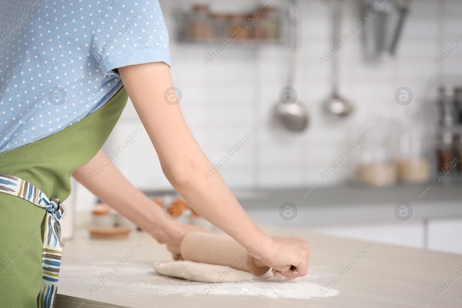 Photo of Woman rolling dough at table in kitchen, closeup