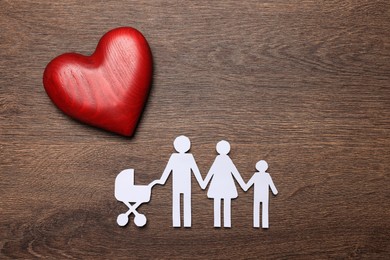 Photo of Paper family cutout and red heart on wooden background, flat lay. Insurance concept
