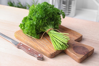 Photo of Wooden board with fresh green parsley on table