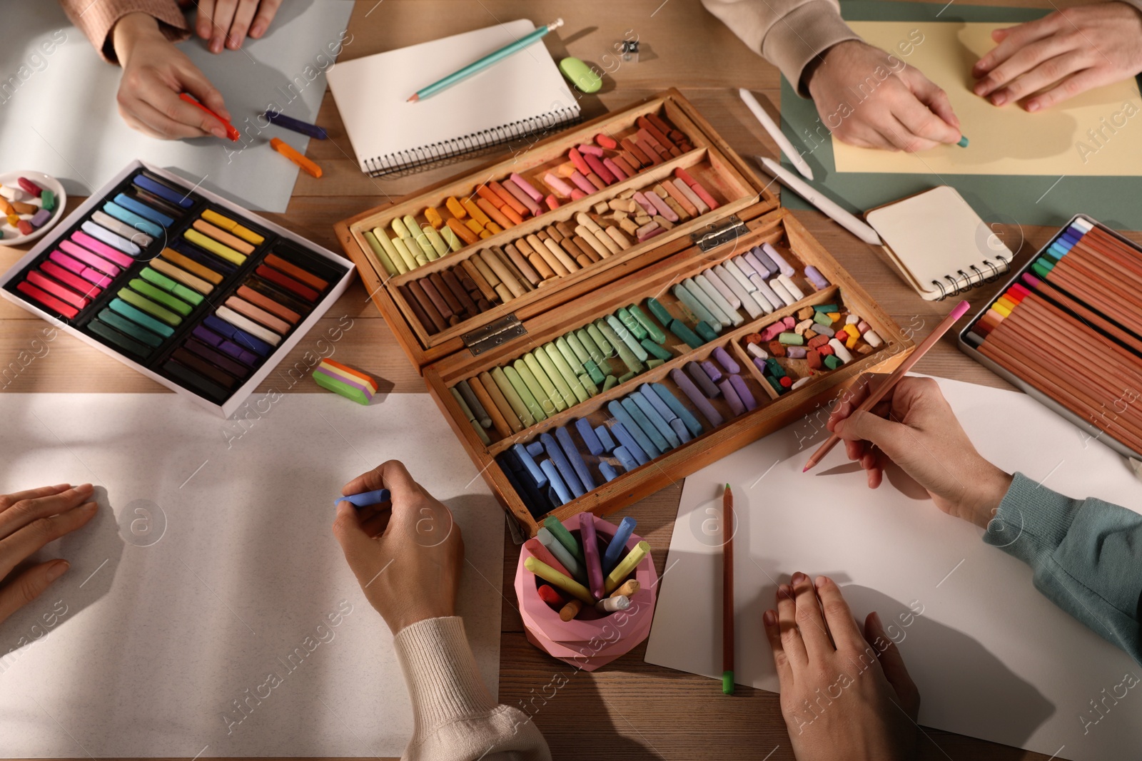 Photo of Artists drawing with soft pastels and pencils at table, above view